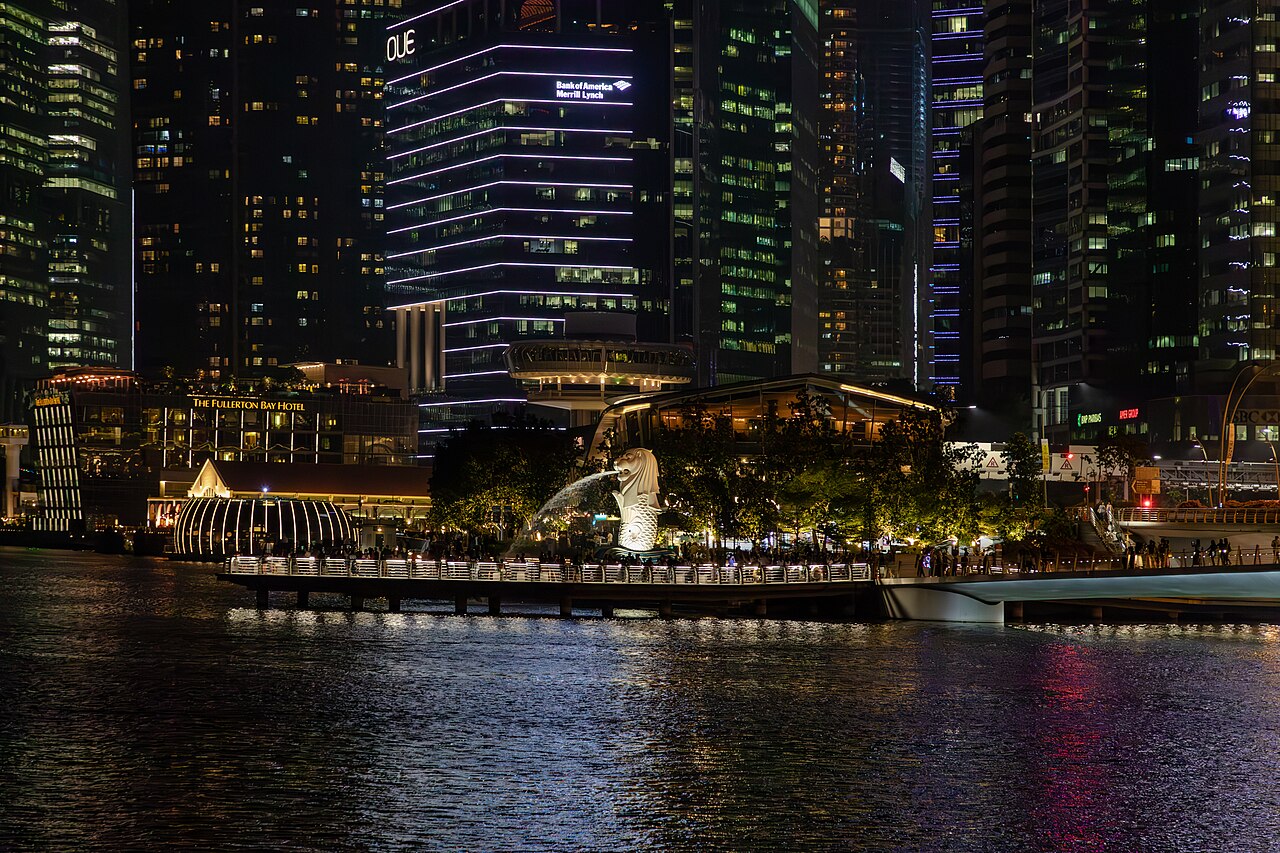 The Merlion statue lit at night in front of the Singapore waterfront
